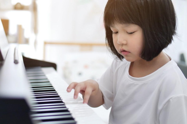 ピアノの鍵盤に触れる女の子