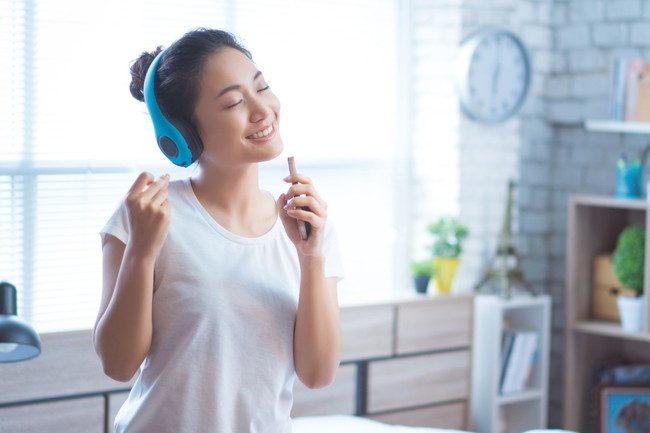 ペンをマイク代わりにして歌う女性