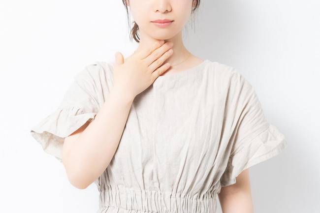 喉を手で押さえる女性
